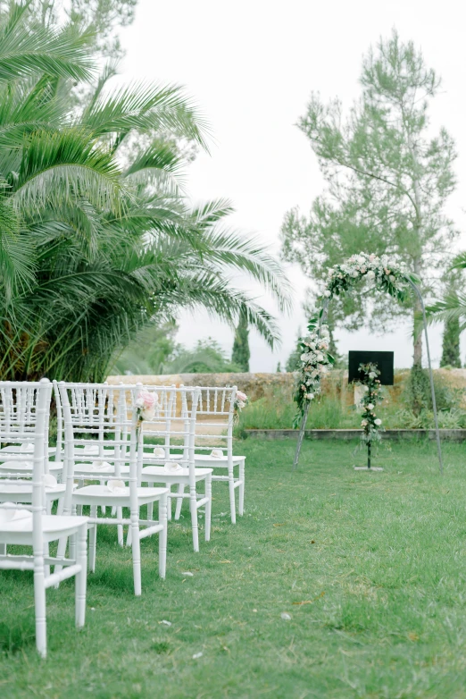 rows of white chairs sit in the grass