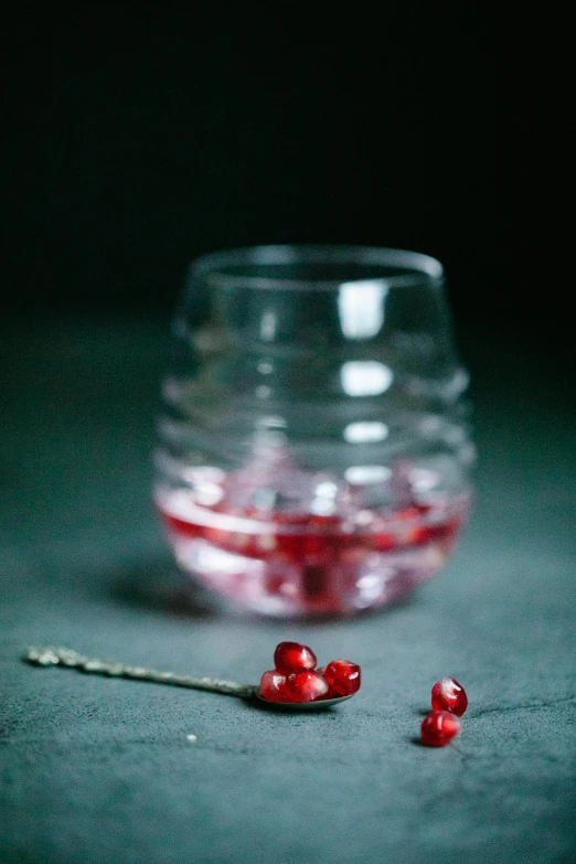 red candy candies in a clear bowl beside some tiny plastic strawberries