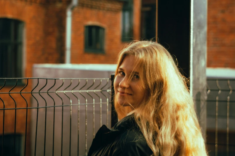 woman on phone, standing by iron fence, wearing black shirt