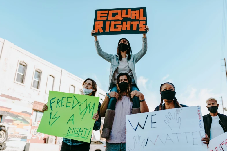 a group of people holding signs protesting and wearing masks