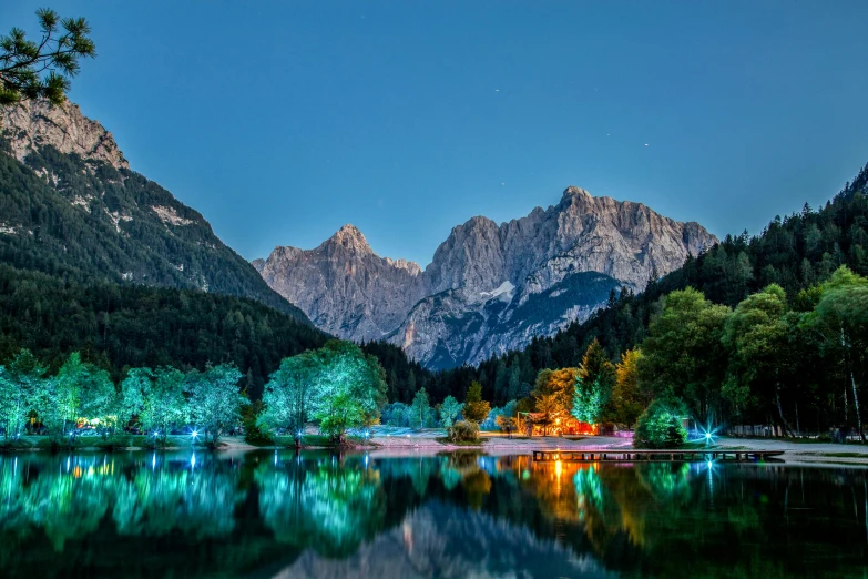 a mountain range reflected in a pond with lights shining on them