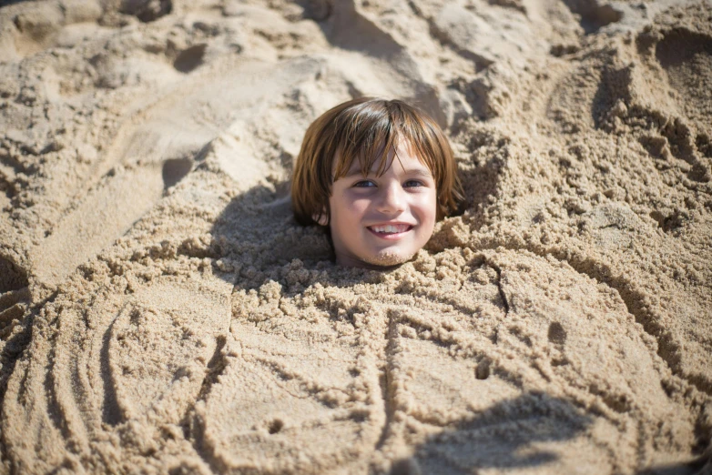 a  laying in the sand, smiling and looking at the camera