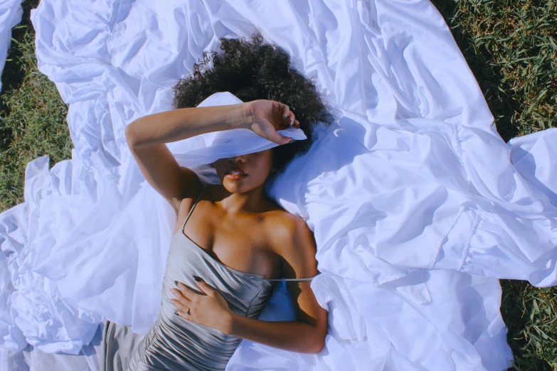 a woman lying on a sheet of white fabric