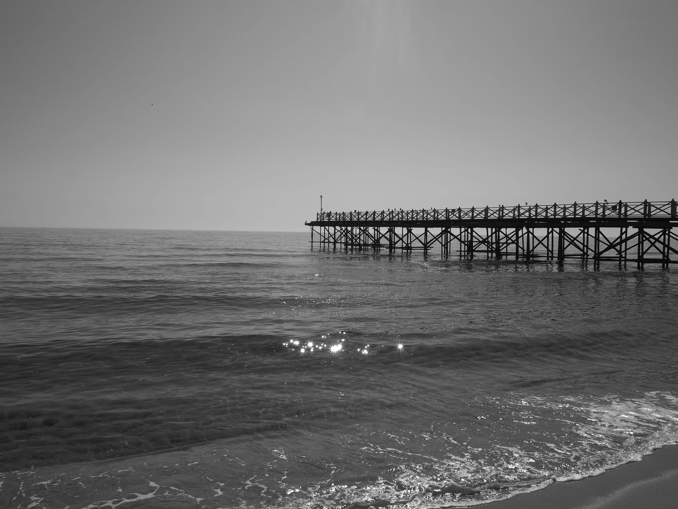 a pier sits near the ocean as waves roll by