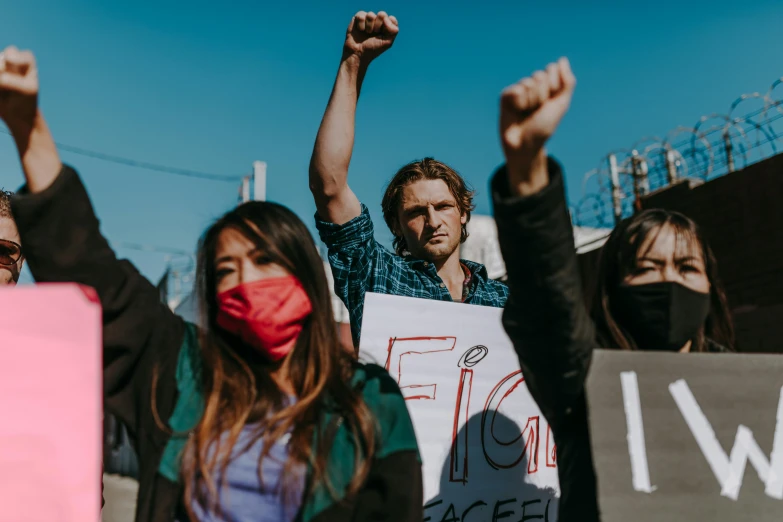 group of people holding signs wearing face masks