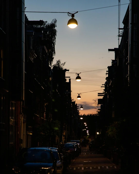 a street at dusk with some lights hanging above it