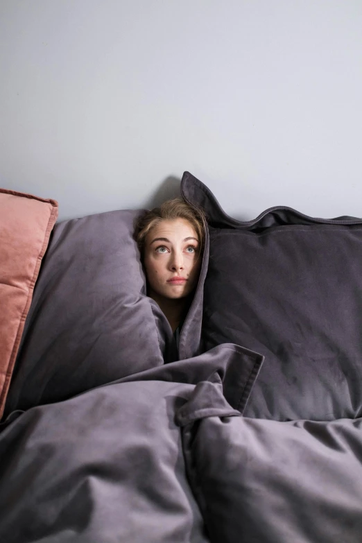 a woman in bed peeking out from under the blanket