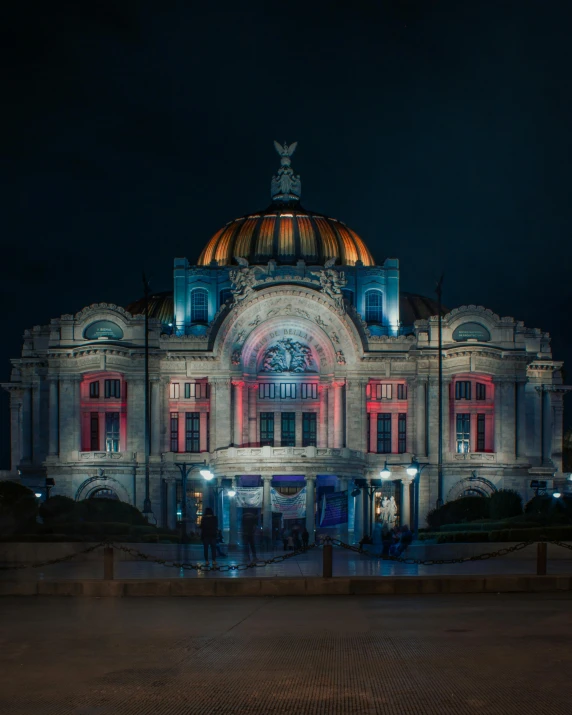 an architectural view at night of a building that has some red lights and blue dome