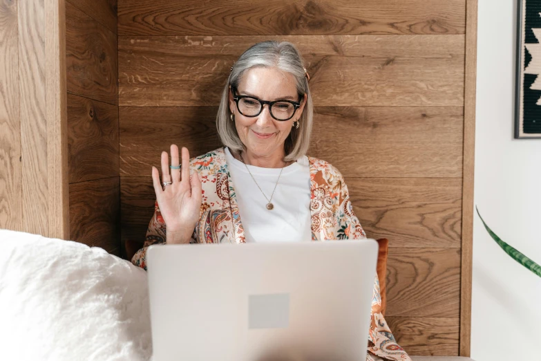 older lady with glasses using laptop sitting on the bed