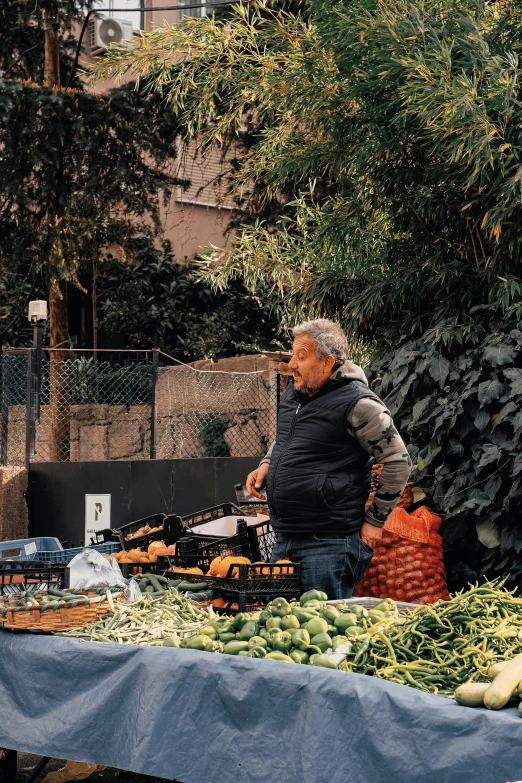 a man stands by vegetables at an outdoor market