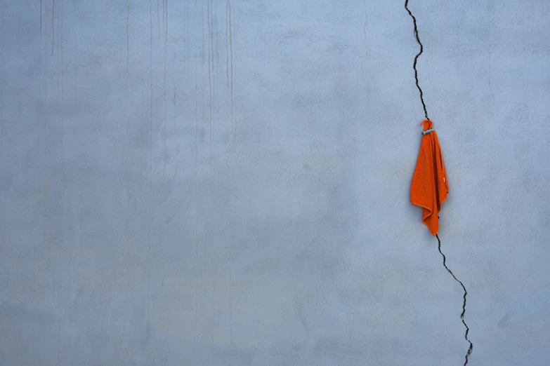 a pair of orange umbrellas next to a concrete wall