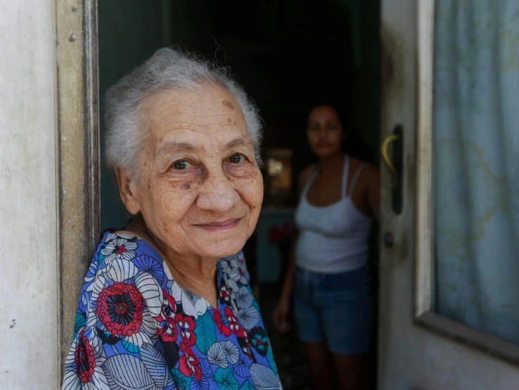 the old woman stands in a doorway while a younger women walks outside