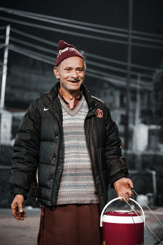 a man with a backpack and skis smiles in the street