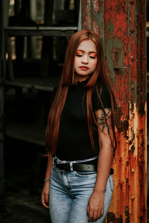 a girl with very long hair standing next to a rusted building