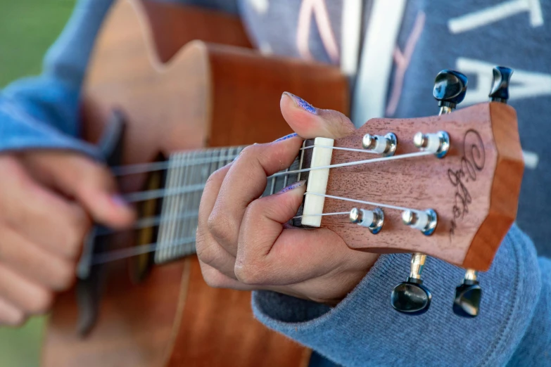 the fingers of someone with blue nail polish are playing an acoustic guitar