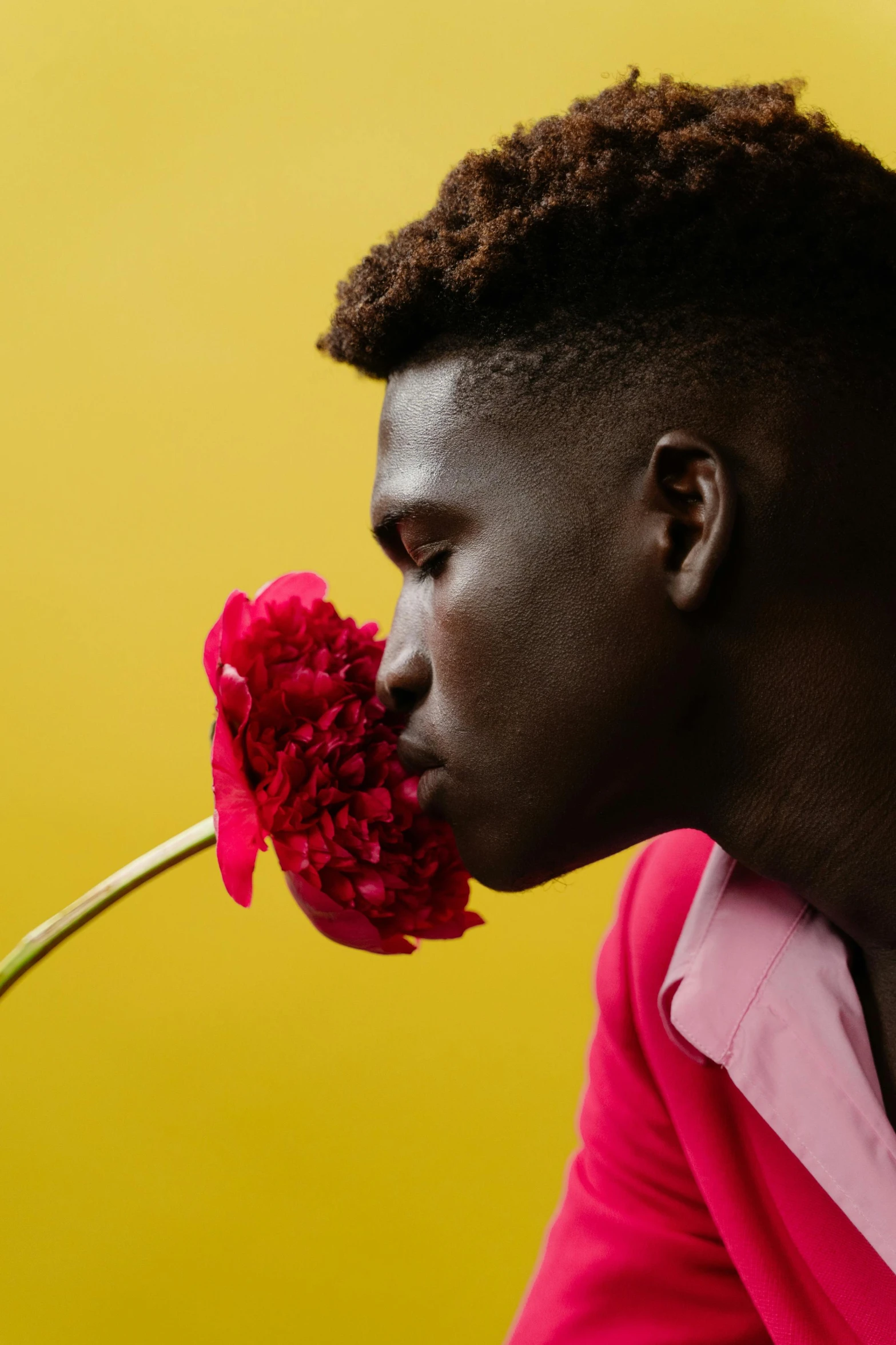 a man with short hair with a flower in his mouth