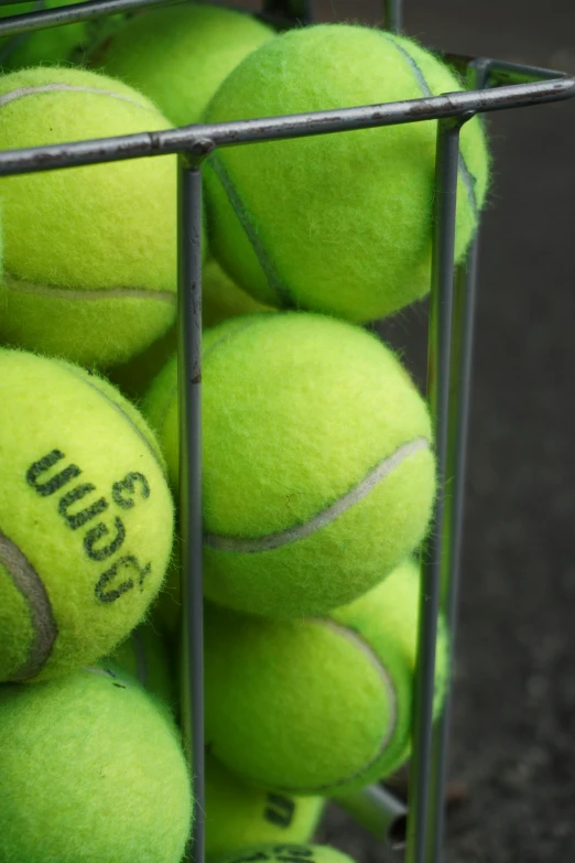 a close up view of a wire basket with several tennis balls in it