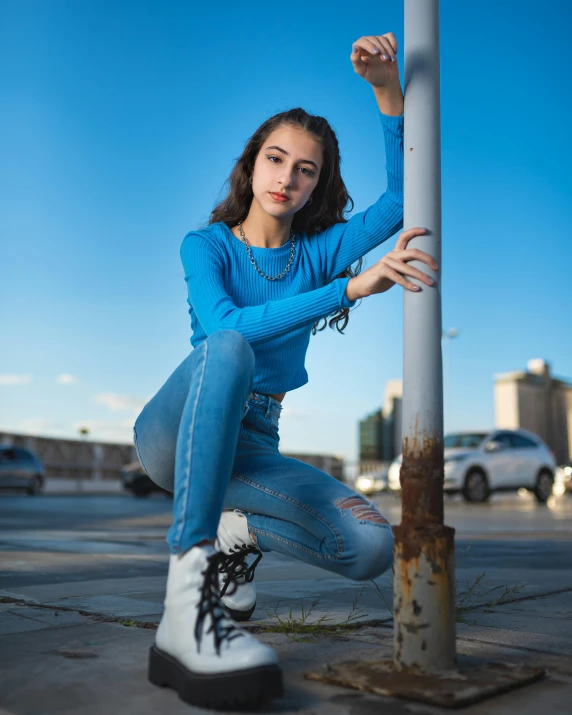 a young woman leaning against a pole