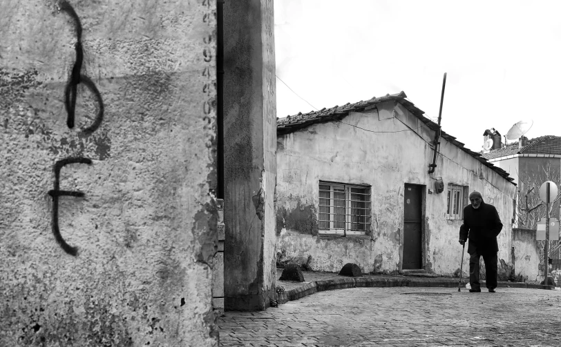 a black and white image of a man walking toward a building