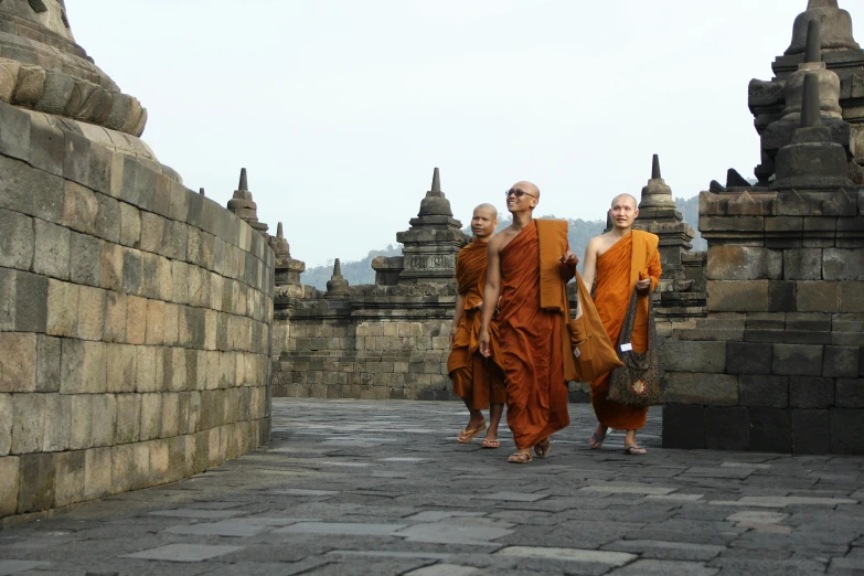 four monks walking down the street in a temple