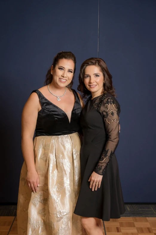 two women are standing in front of a blue wall