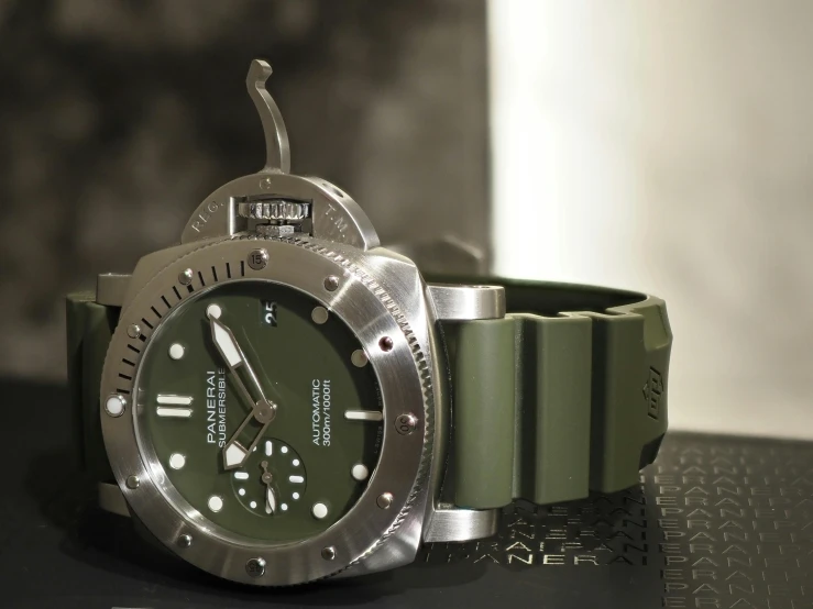 a green watch with a silver case on a table