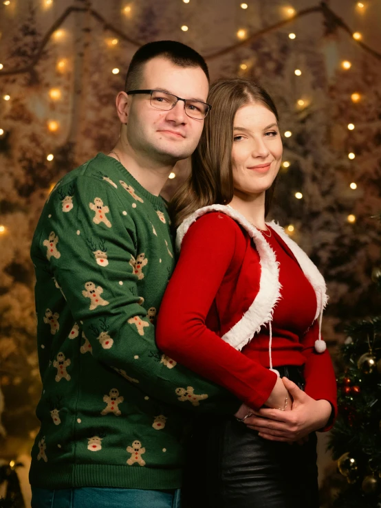 a woman and man posing in front of a christmas tree