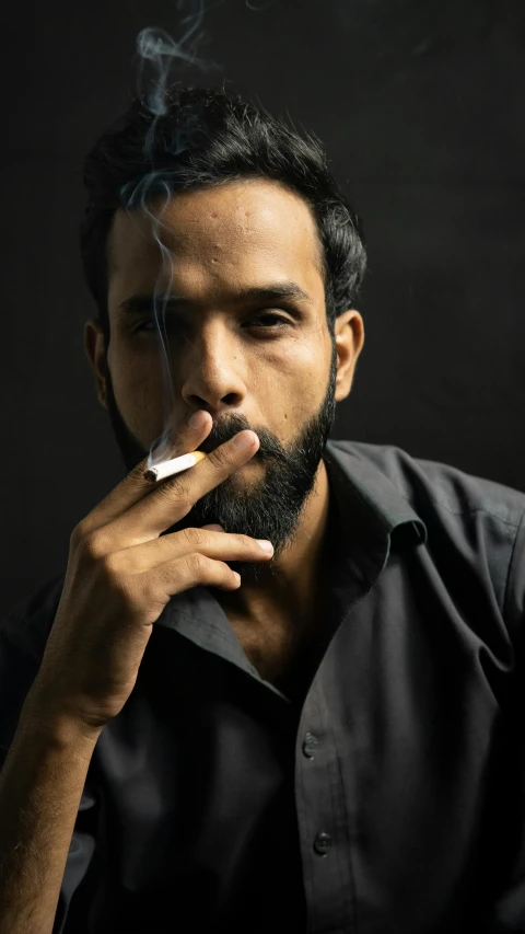 a man smoking while sitting on the ground