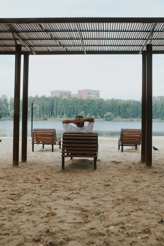 two people sitting on wooden benches on the beach