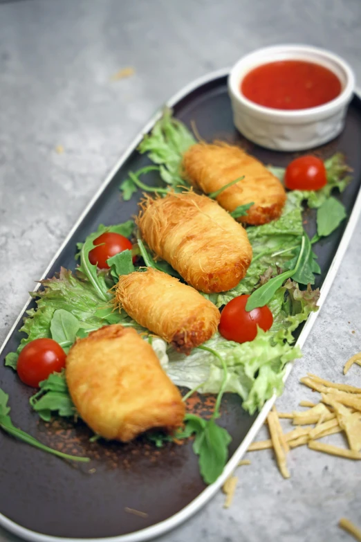 a long plate with food on it, containing fish and salad