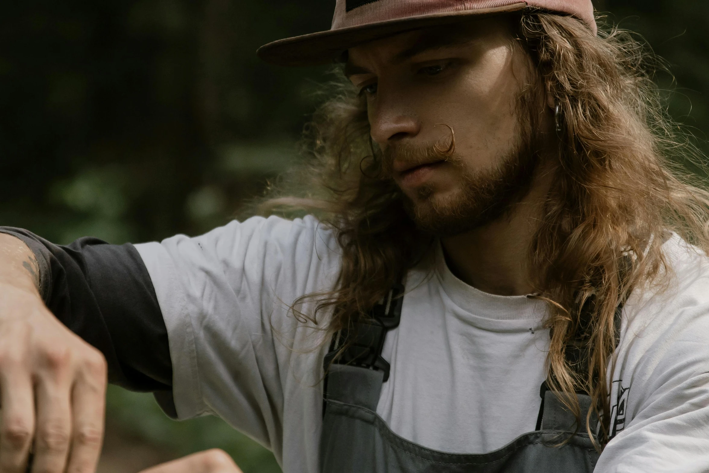 a man with a long, red hair wears an apron and hat