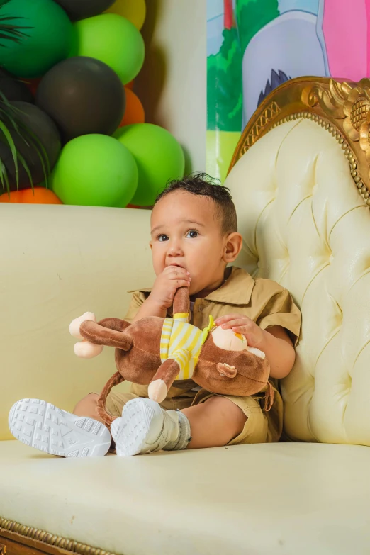 a small child sits on a chair holding a stuffed monkey