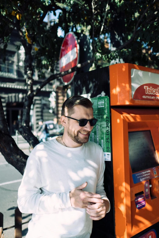 man smiling and standing next to a pay pay machine