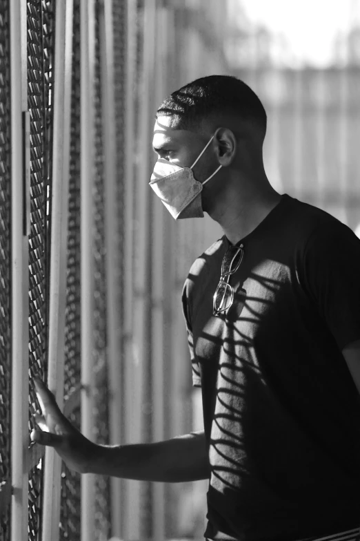 the man is wearing a face mask and holding onto the barbwire fence