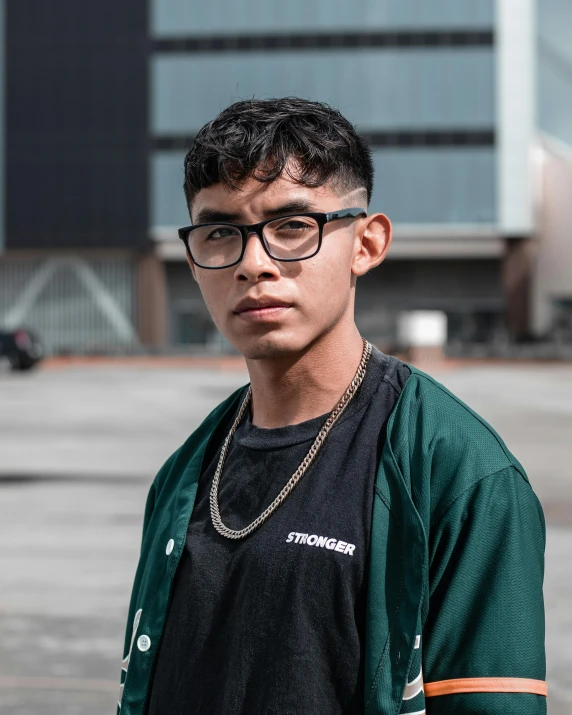 a young man with glasses wearing a green cardigan