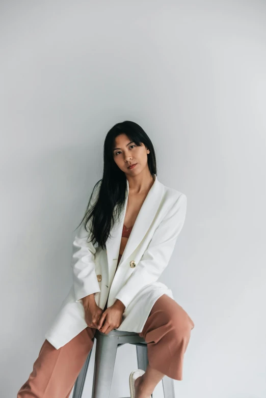 a woman wearing white sitting on a stool