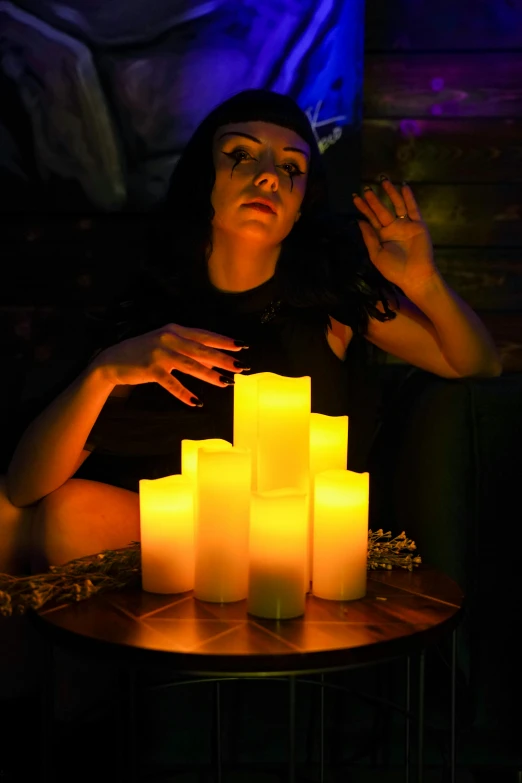 a girl sitting in front of a table of lit candles