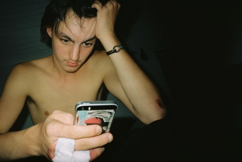 a shirtless man checking his cell phone