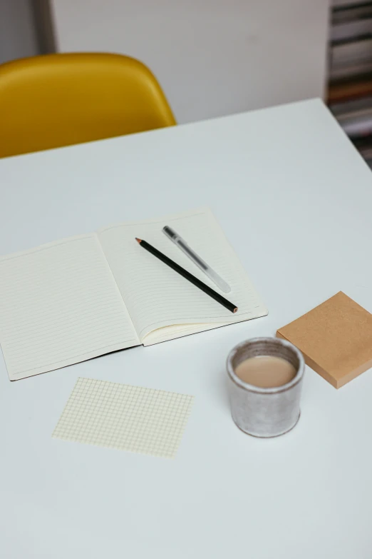a notebook with an ink can and two markers sit on a table