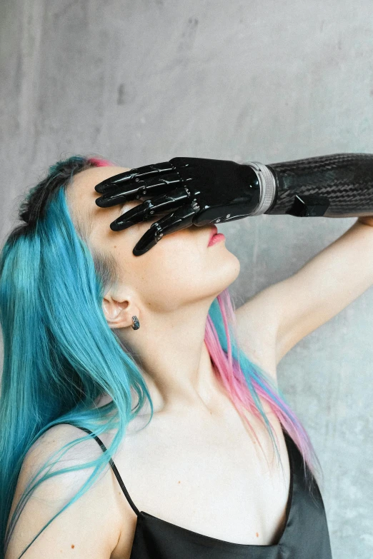 woman with blue hair wearing a black dress looking through her fingers