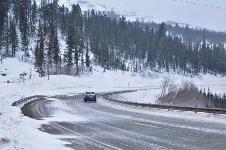 a car on the snow covered road in the mountains