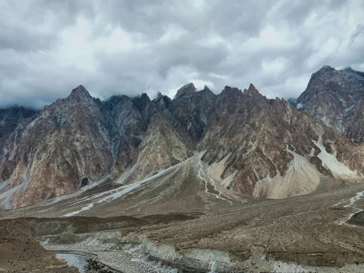 there is a mountain range under clouds with snow