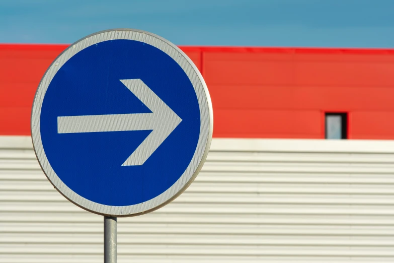 a blue road sign points towards an arrow