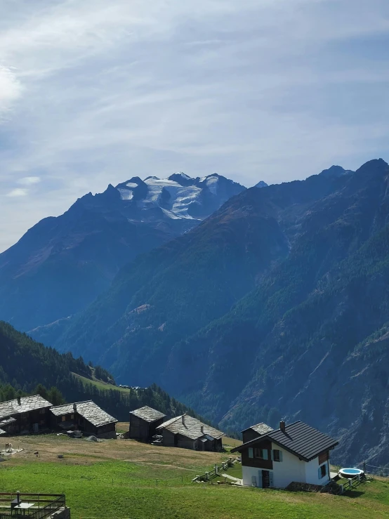 a field with a small building in the middle and mountain on the side