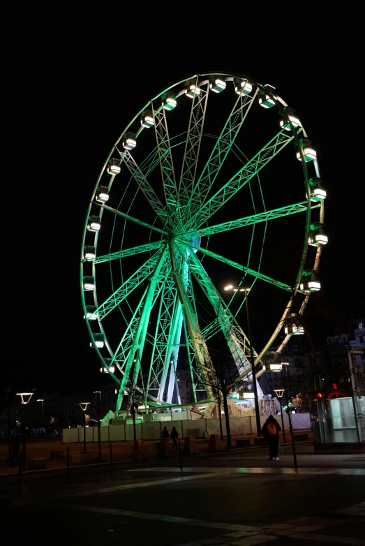 a ferris wheel that is green on a dark street