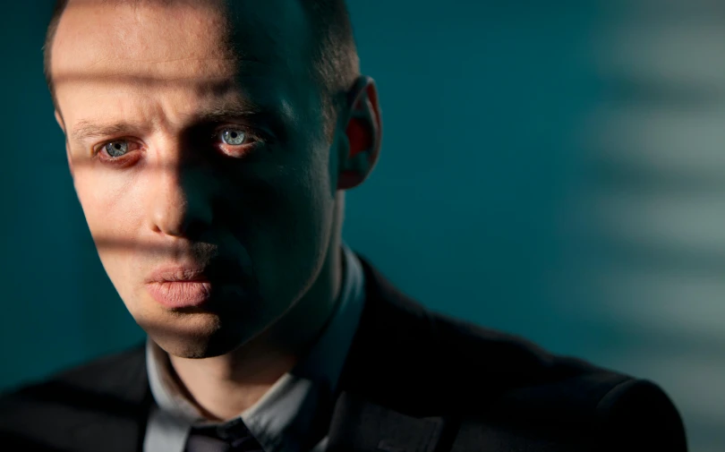 man wearing a dark suit and grey shirt with tie