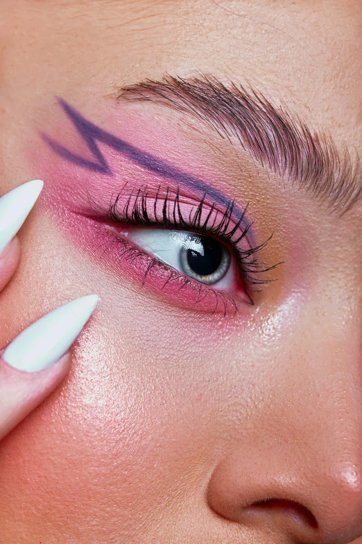 a woman with pink and red makeup has her hand on her face