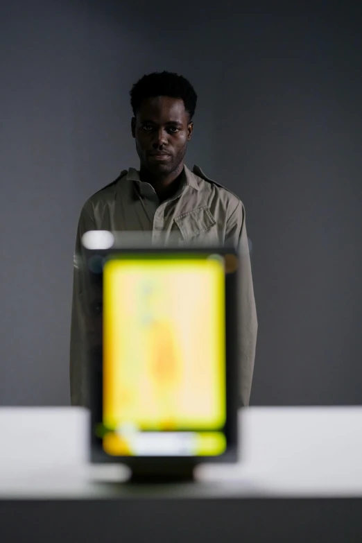 a man wearing glasses standing next to a computer screen