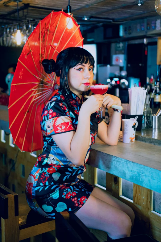 an asian lady is sitting at a bar and drinking a beer