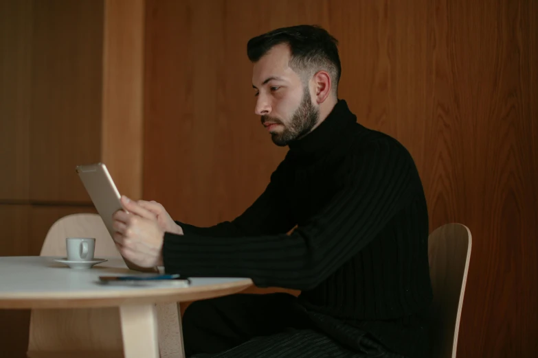 a man sitting at a table reading on a tablet